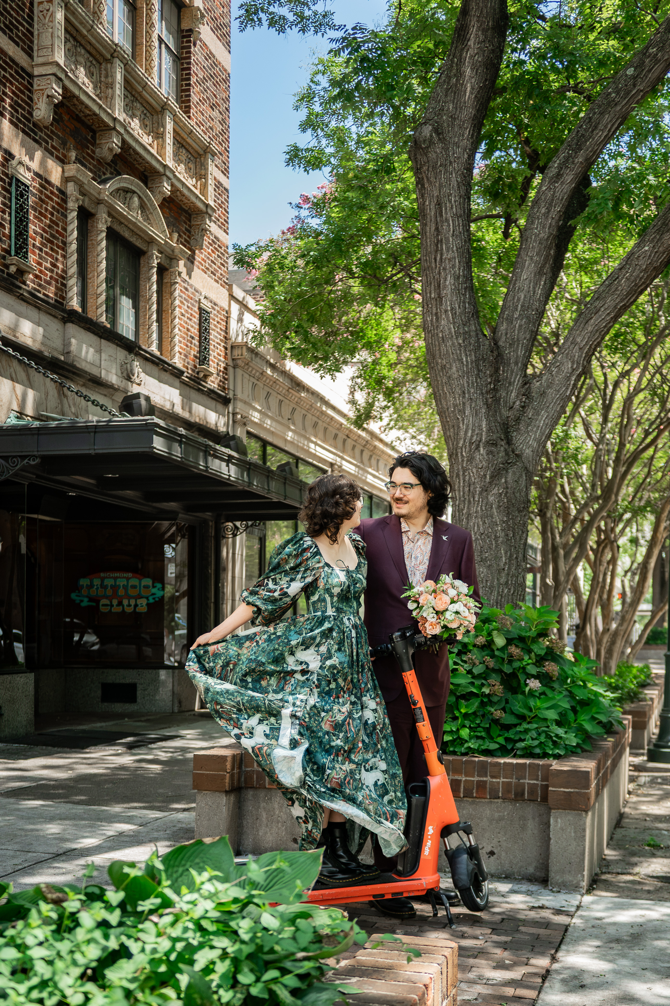 The two of us on a tree-lined sidewalk in downtown Richmond, one of us holding a bouquet.